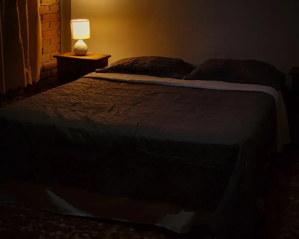 Interior de una cabaña de Hotel El Pantano, con cama matrimonial y luz natural